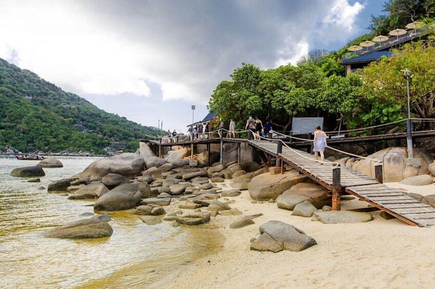 Una spiaggia rocciosa con una passerella di legno e persone che passeggiano. 4