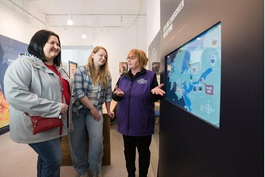 Three people standing in front of a digital display with abstract graphics. 1