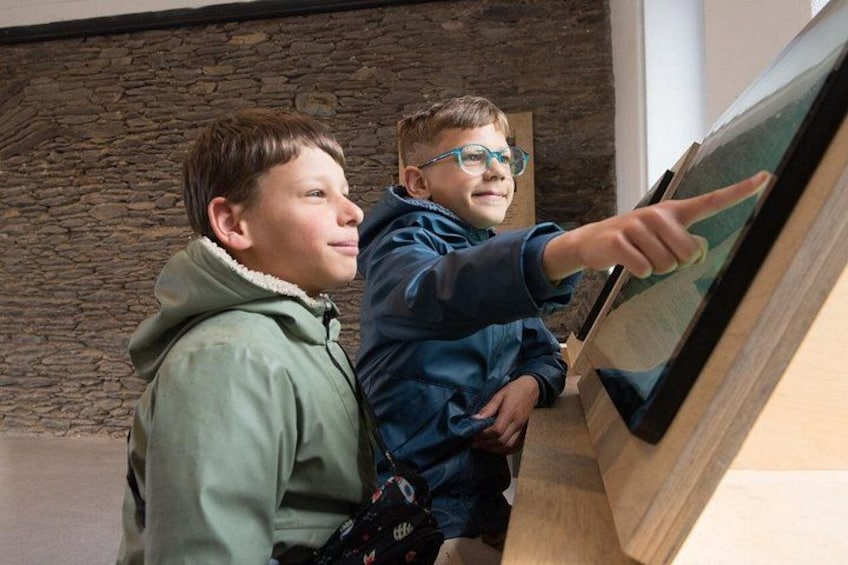 Two children looking at a display case with a stone wall background. 4