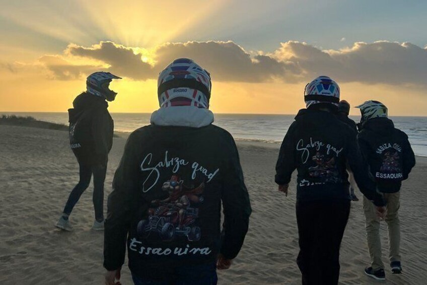 Four people walking on a beach during sunset. 5