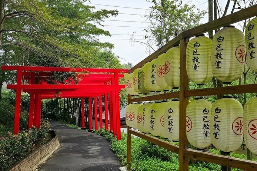 A red torii gate pathway leading to a shrine, surrounded by greenery. 2