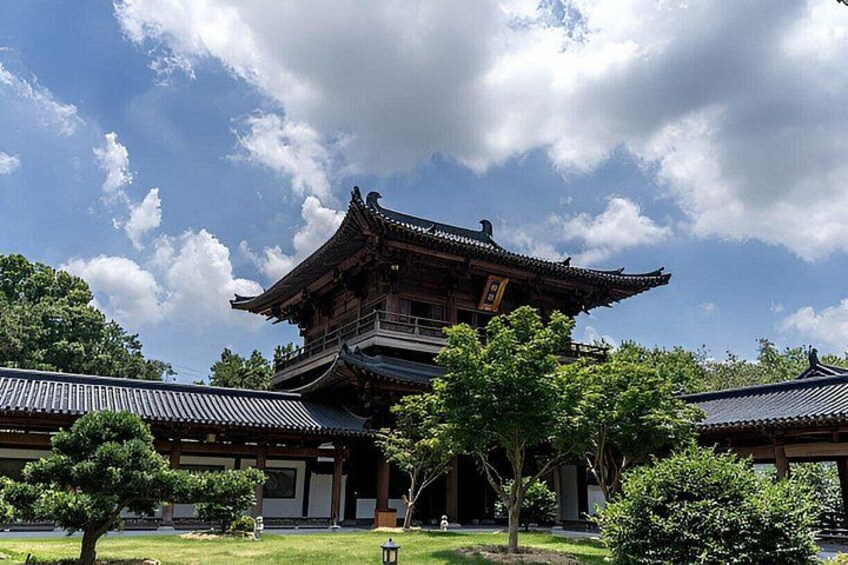 A traditional Japanese building with a multi-tiered roof, surrounded by well-maintained trees and a clear sky. 1