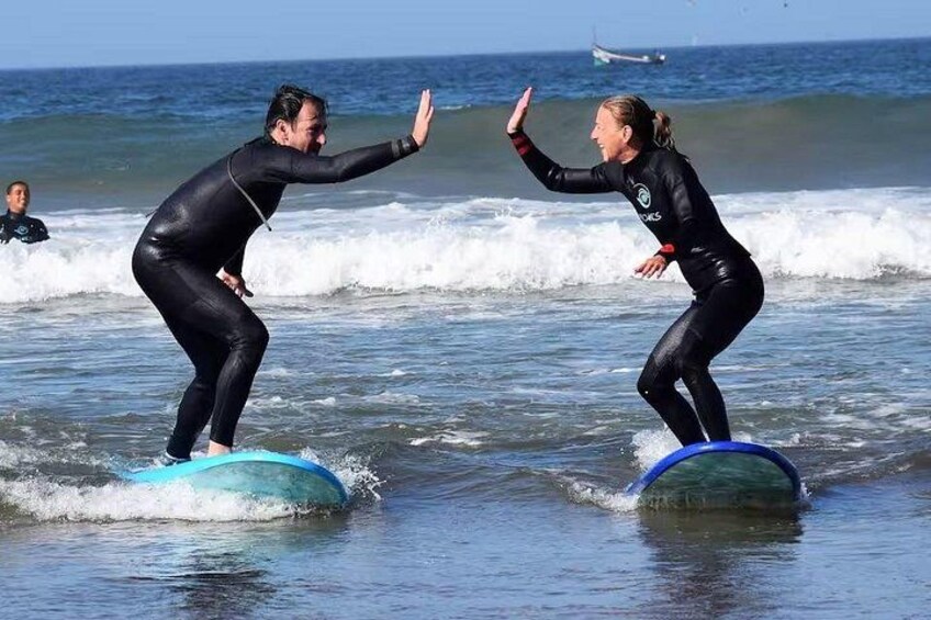 Two people surfing on a calm ocean with waves. 1