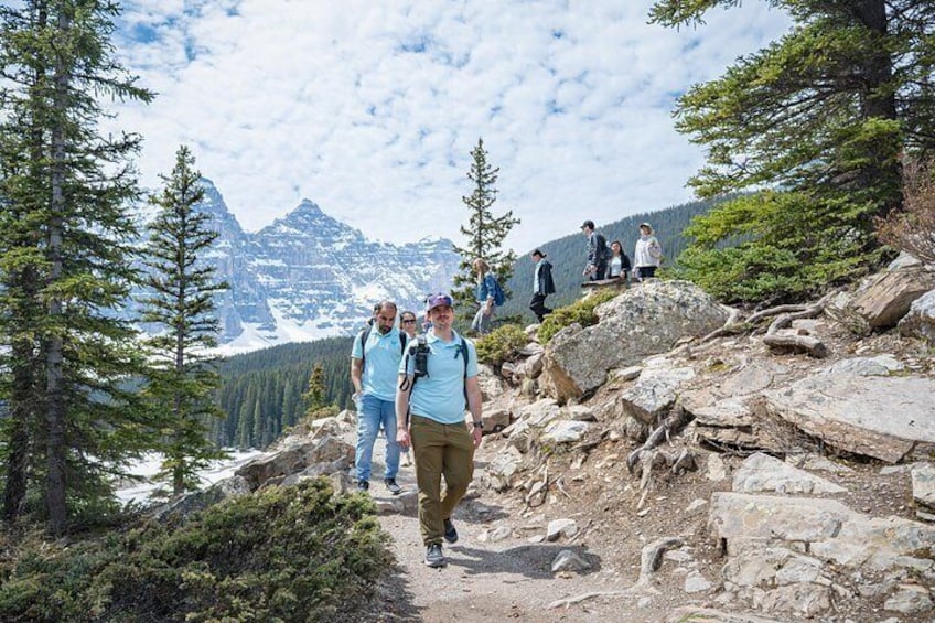 Hikers on a rocky trail with snow-capped mountains in the background. 5