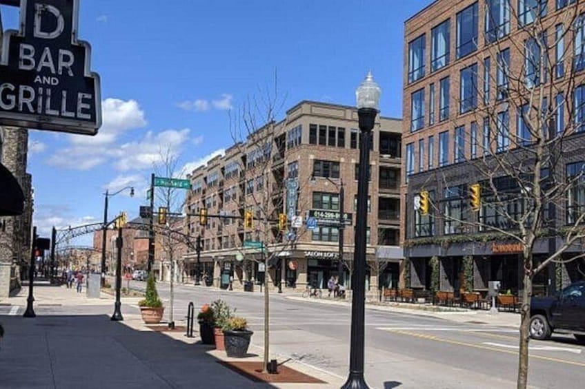 A city street with buildings, a bar sign, and a street lamp. 2