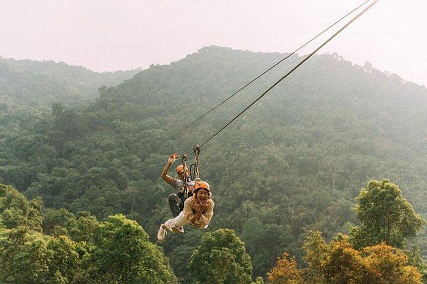 To personer svæver i zipline over et skovklædt bjergområde. 5