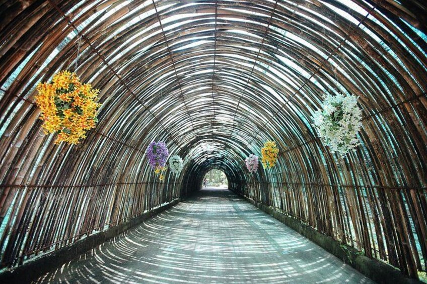 En tunnel med et buet metal tag og blomsterdekorationer hængende fra loftet. 3
