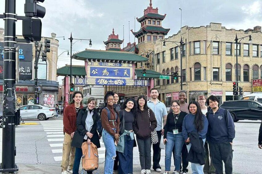 En grupp människor står vid ett övergångsställe framför en traditionell byggnad med ett tak i pagodstil. 5