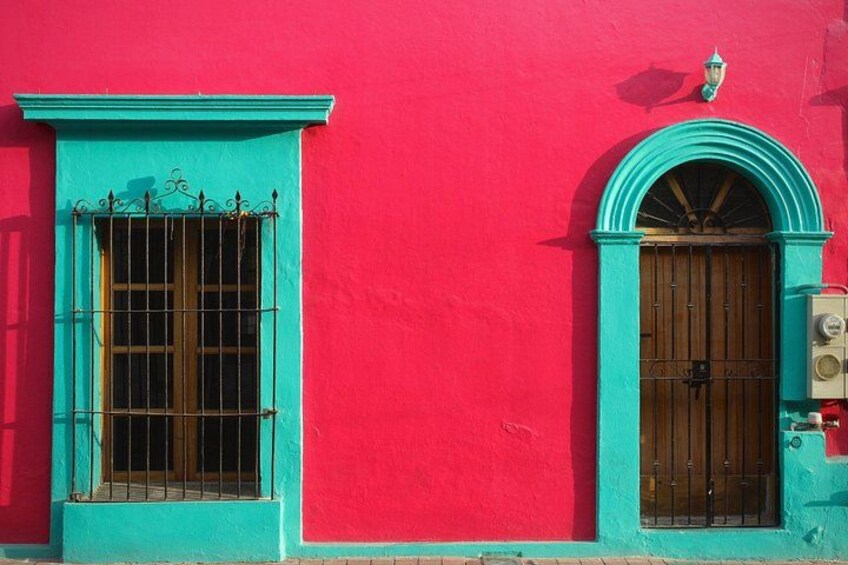 A red building with turquoise window frames and a wooden door. 1