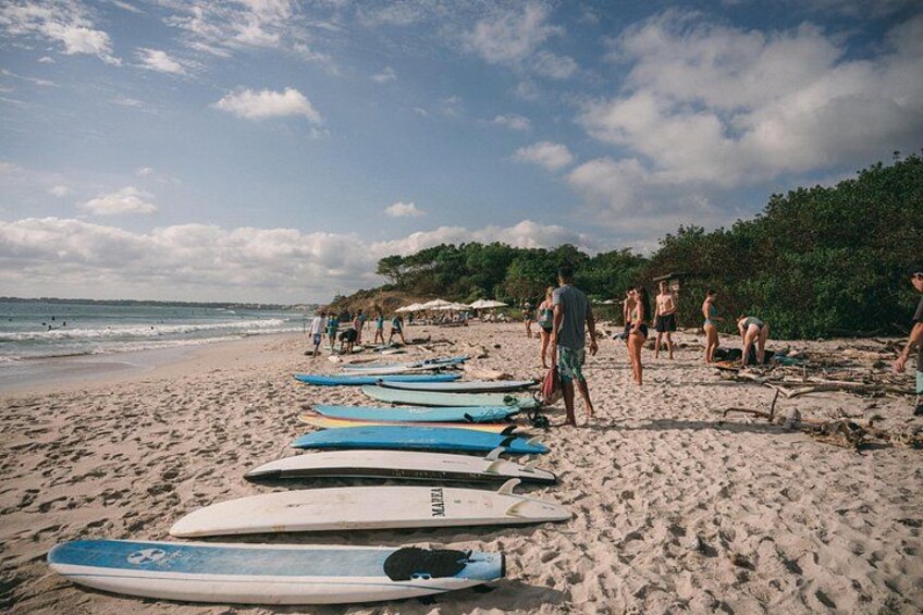 A beach with surfboards lined up and people walking. 3