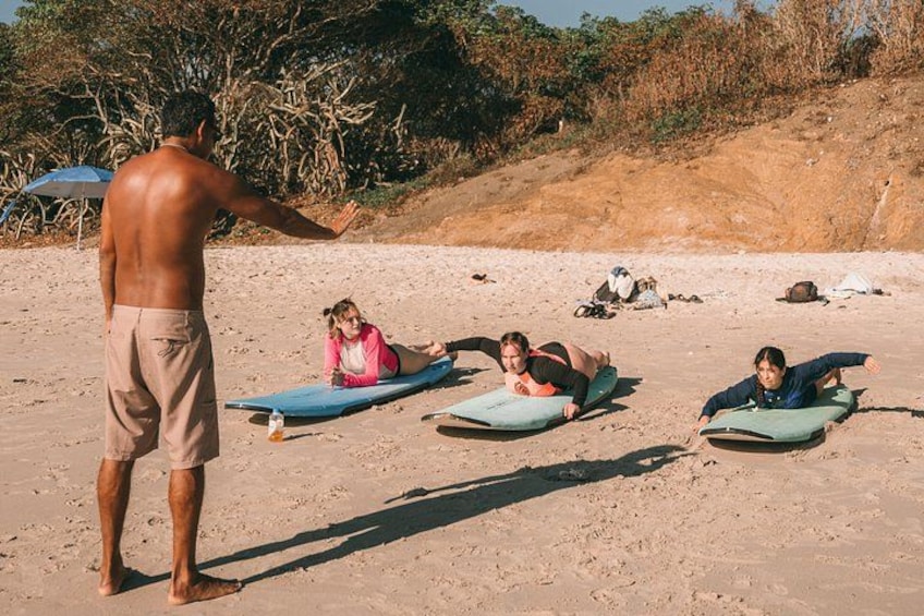 A person teaching yoga on a sandy beach with three students lying on mats. 2