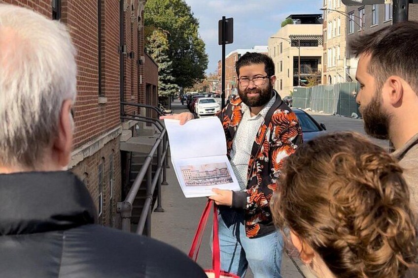 A person holding a map, standing on a sidewalk with buildings and a street in the background. 1
