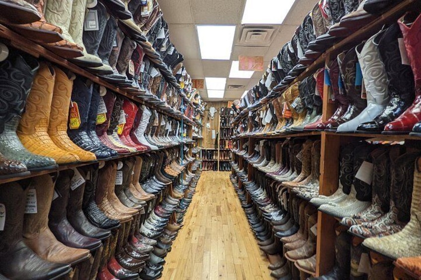 A store aisle with rows of boots on shelves. 5