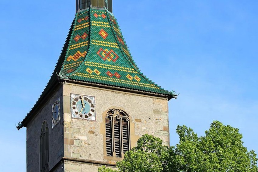 Et tårn med et ur, et spids tag og en murstensfacade. 1