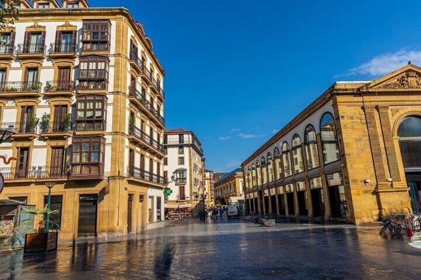 A historic street with ornate buildings, a wet pavement, and a clear blue sky. 5