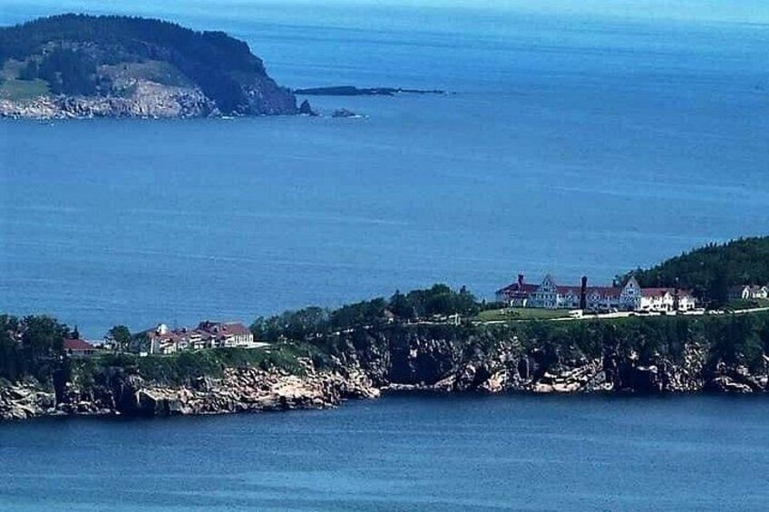 A coastal landscape with rocky cliffs, a body of water, and a cluster of buildings on the shore. 2