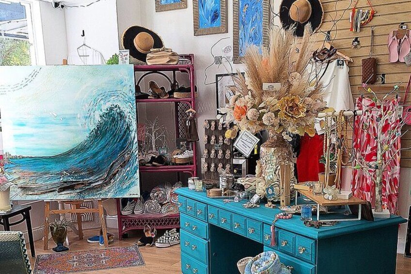 A room with a large painting of a wave, a blue dresser, and various decorative items. 1