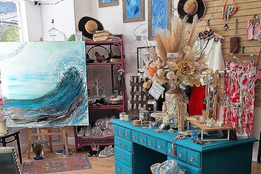 Una habitación con un cuadro grande de una ola, un aparador azul y varios objetos decorativos. 1