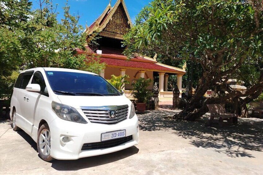 A white minivan parked in front of a traditional building with a red roof. 2