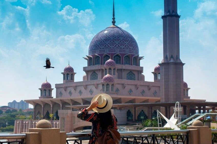 A large mosque with a prominent dome and minarets, a person in traditional attire, and a bird flying in the sky. 4