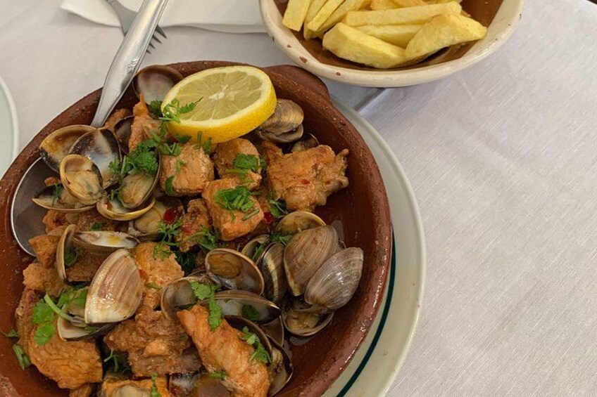 En skål med muslinger og fisk pyntet med persille, serveret med citron og pommes frites. 3