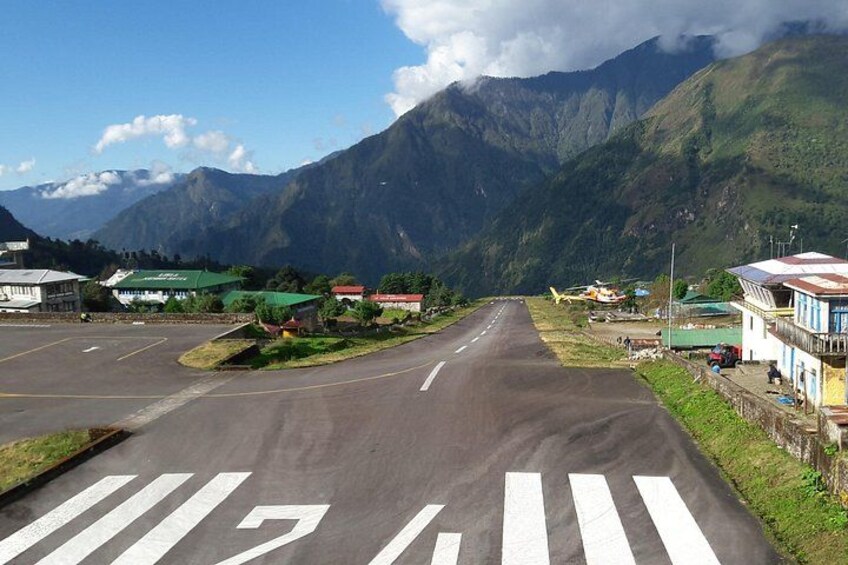 A road with a pedestrian crossing, buildings, and mountains in the background. 3