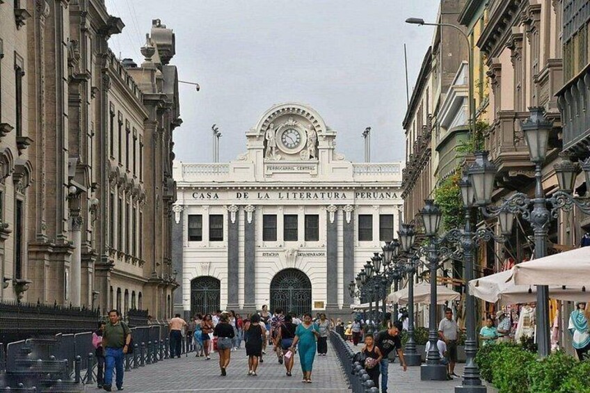 A historic building with a clock tower, surrounded by pedestrians and street lamps. 3