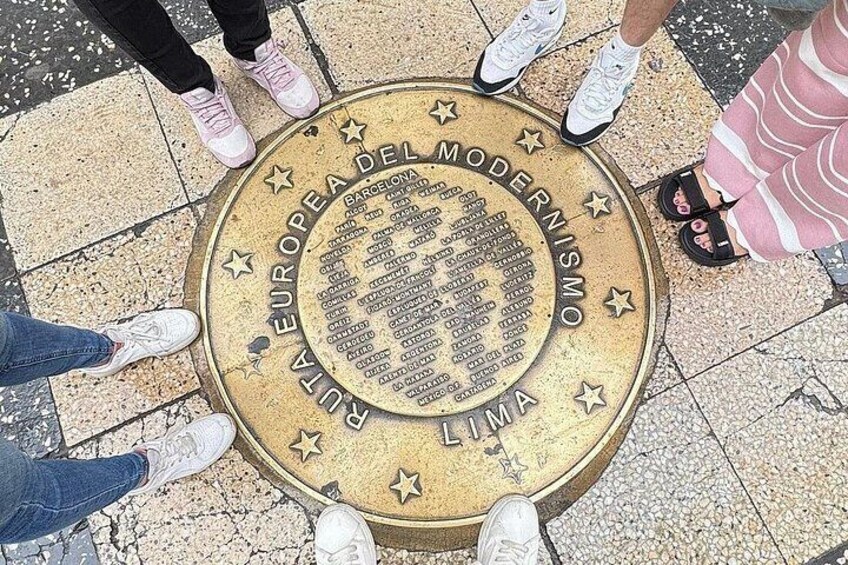 A circular plaque with text and stars, surrounded by people standing around it. 4