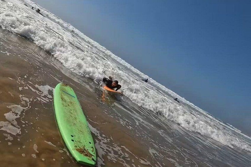 A beach with waves, a green surfboard, and a person in the water. 3