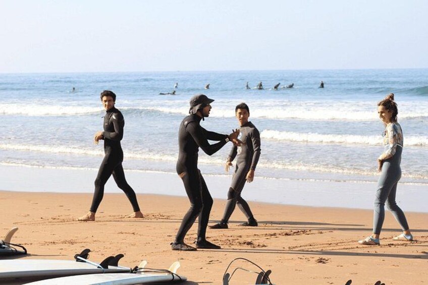 People walking on a beach with surfboards and a surfboard in the foreground. 4