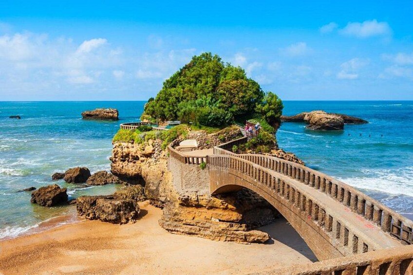 A coastal landscape with a stone bridge, rocky outcrops, and a lush green island. 3