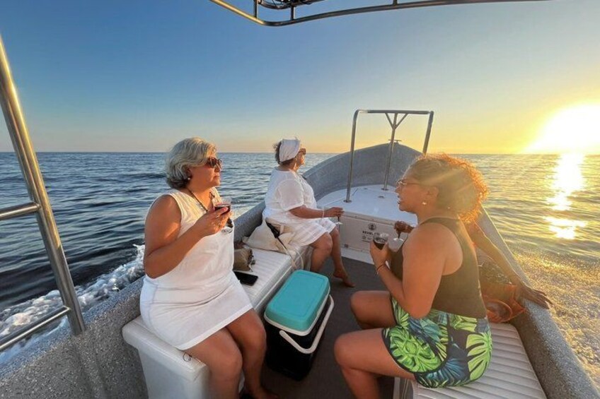 Three people on a boat with a sunset in the background. 1