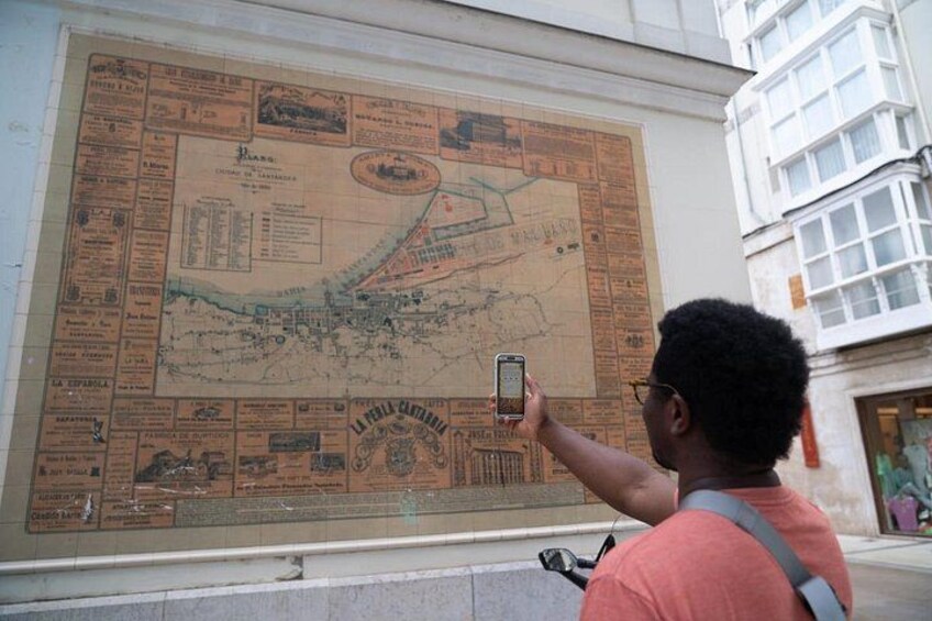 Eine Person fotografiert eine große historische Karte an einer Wand. 3
