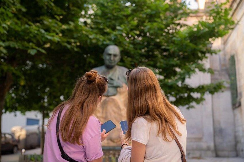 Zwei Personen unterhalten sich vor einer Statue in einer Stadt. 5