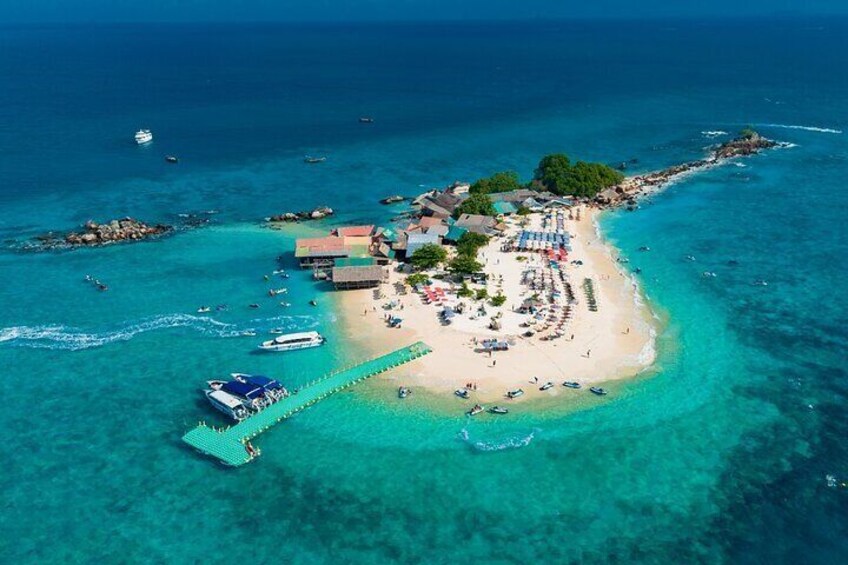 An aerial view of a tropical island with a beach, boats, and a pier. 1