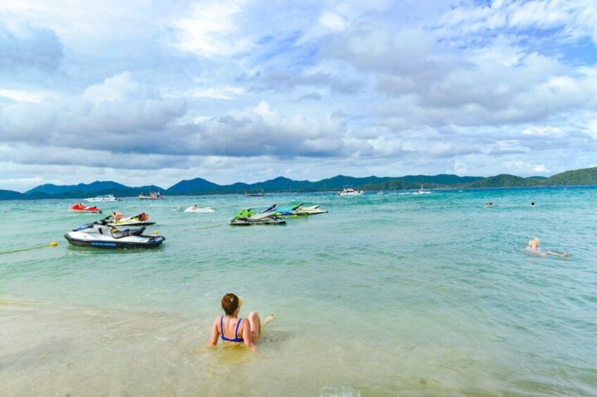 A beach with people swimming and jet skis in the water. 2