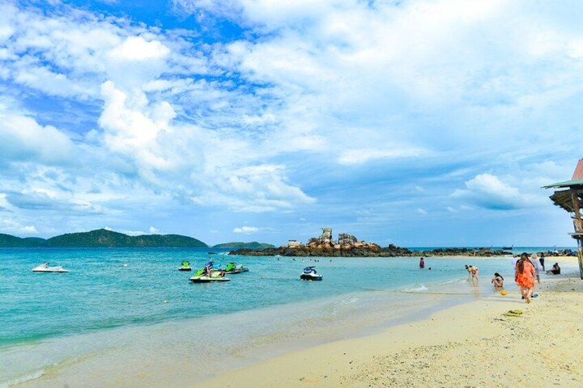 A beach with clear water, boats, and people. 4