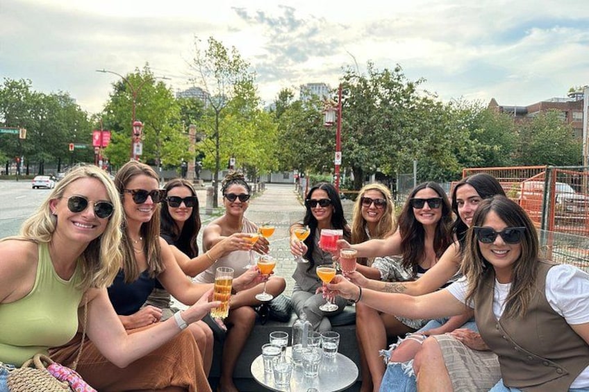 A group of people toasting with drinks at an outdoor table. 1
