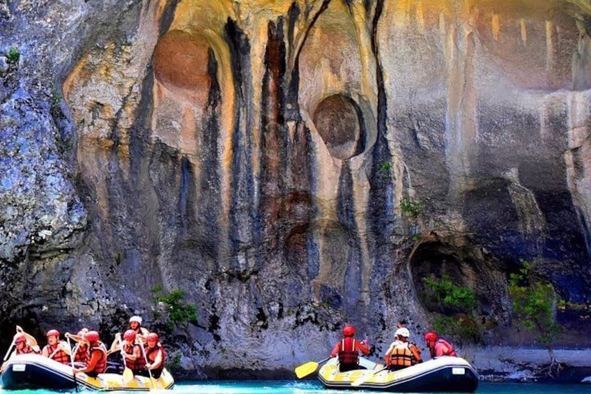 A group of people in a yellow raft navigating a narrow water channel between large rock formations. 2