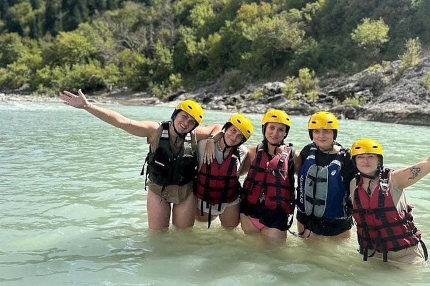 A group of people wearing helmets and life jackets in a river. 3