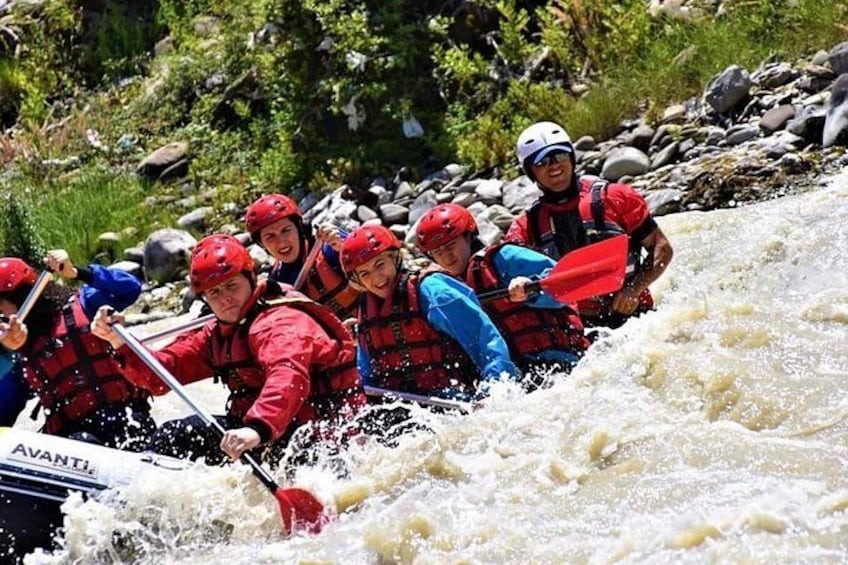 A group of people in a white raft navigating a river with rapids. 4