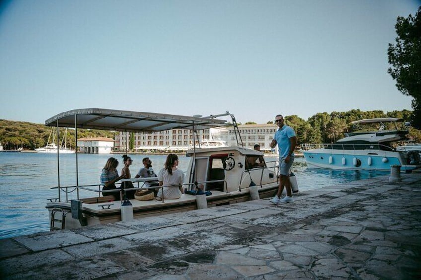 Un barco atracado en un muelle con gente sentada en la cubierta y una persona de pie en el muelle. 2