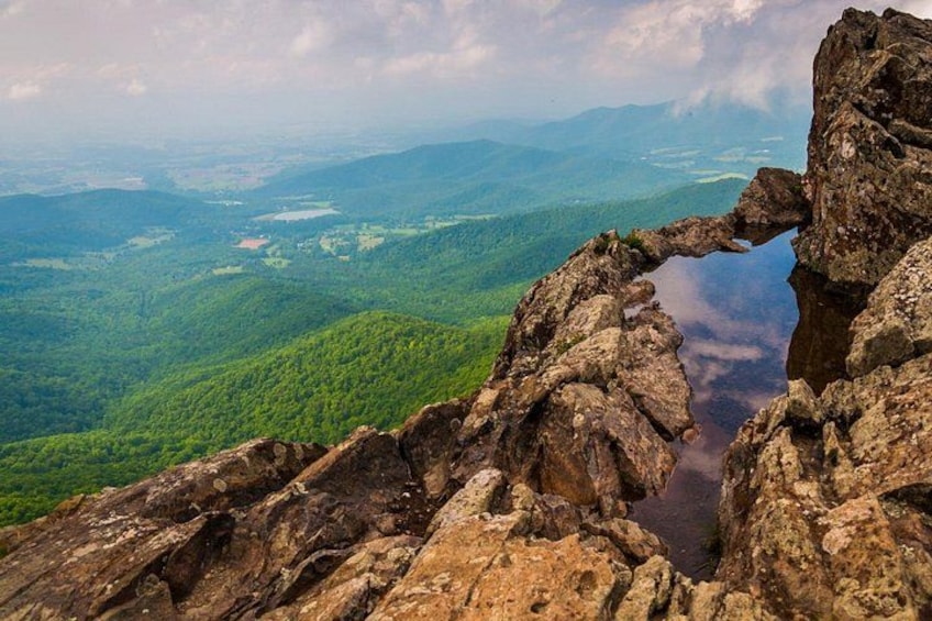 A rocky mountain landscape with a unique rock formation resembling a bridge. 5