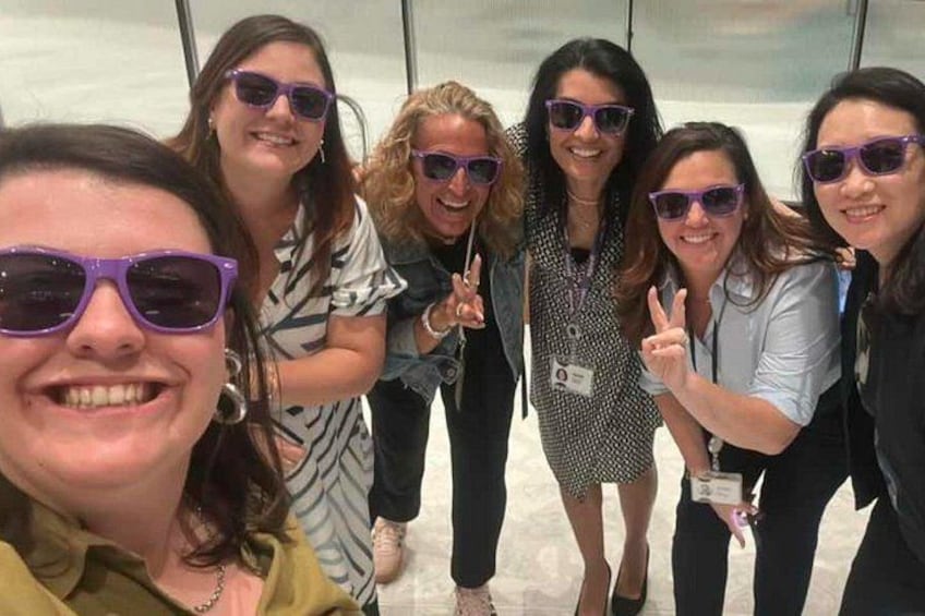 Un groupe de personnes posant pour une photo dans un lieu intérieur, avec un mur de verre en arrière-plan. 2