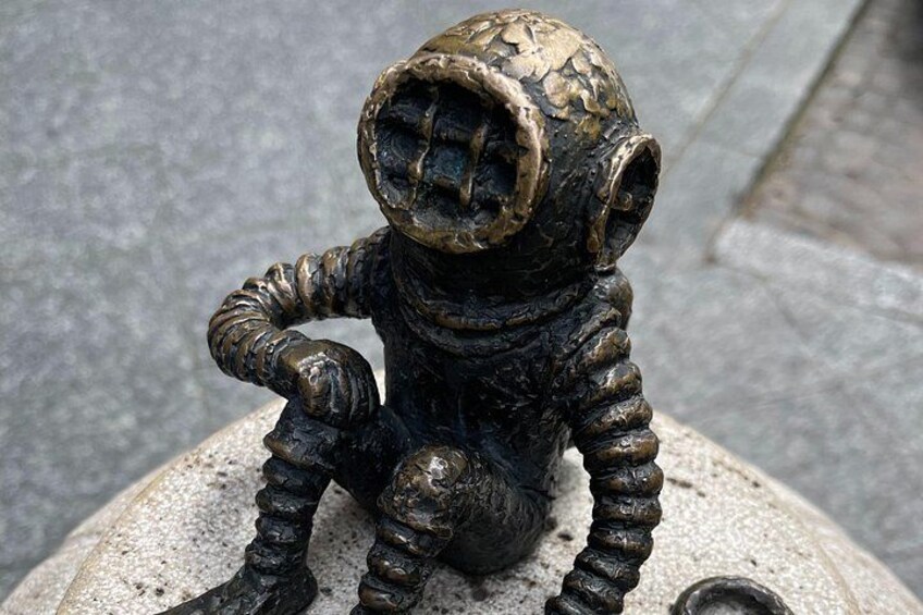 A bronze astronaut figurine sitting on a concrete surface. 4