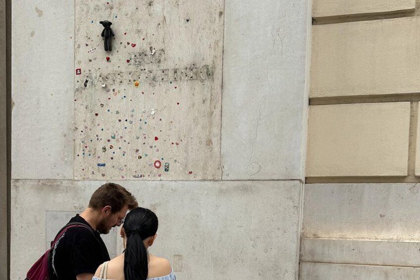 A couple standing in front of a wall with a graffiti-covered section. 2