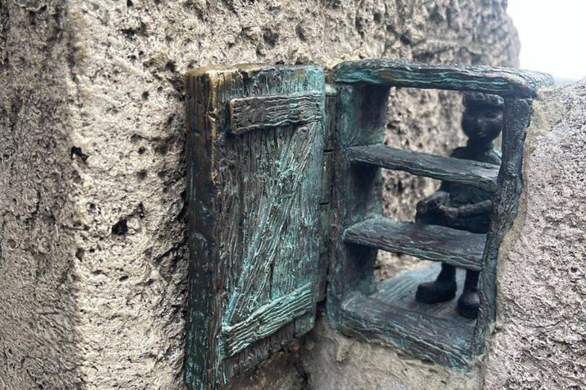 A rustic wooden door with a small window, set in a rough-textured wall. 5