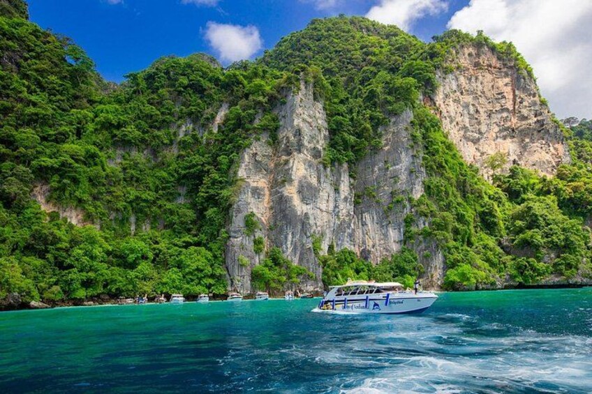A boat on turquoise water, surrounded by lush green cliffs and a clear sky. 3