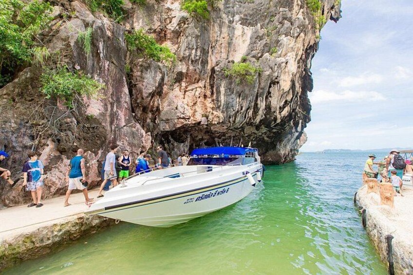 A boat docked at a rocky coastal area with people standing on the shore. 5