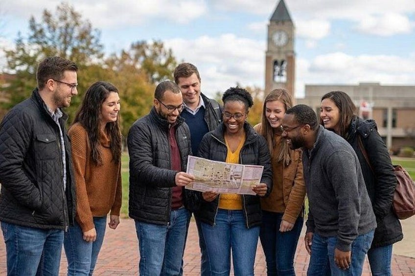 A group of people standing outdoors, some holding a map. 1